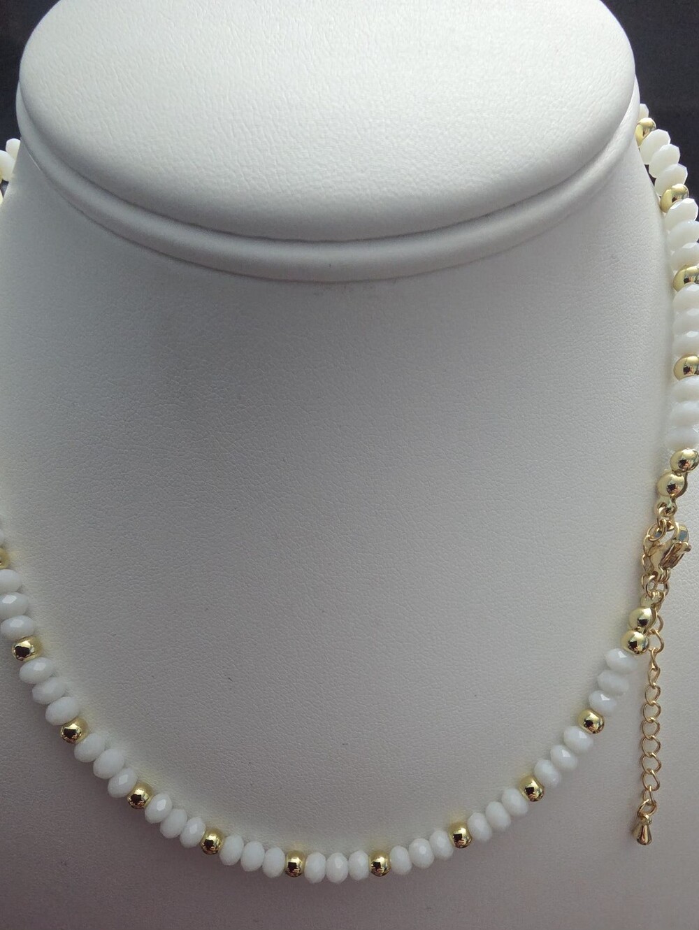white faceted beaded necklace with polished gold tone spacer beads and a pearl s